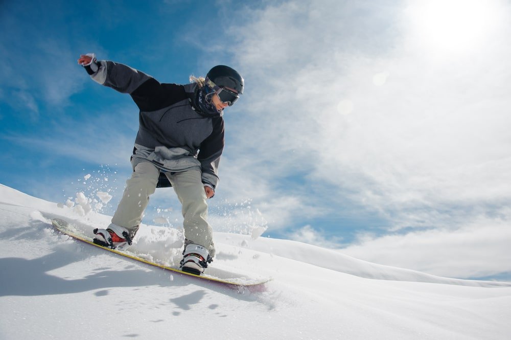 young-female-snowboarder-running-down-mountain-slope-min